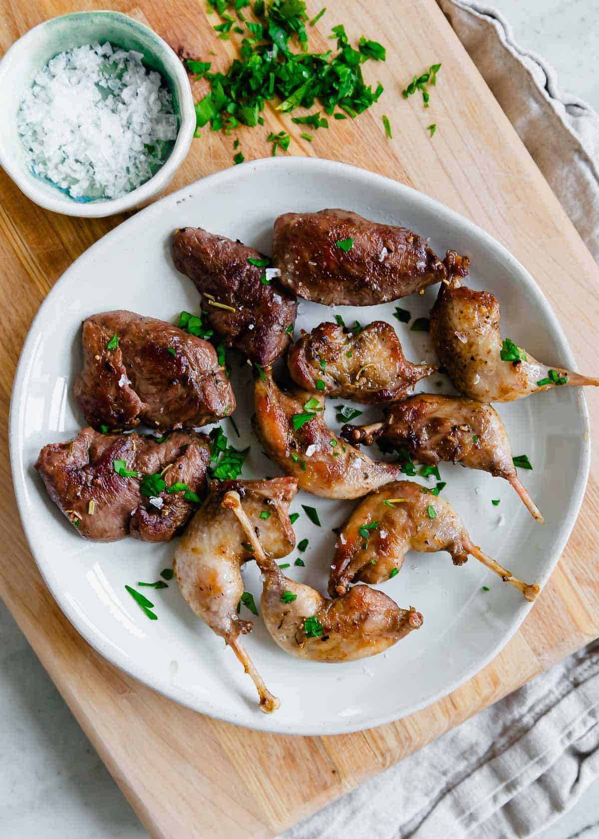 Pan fried woodcock with maldon sea salt and parsley on a plate.