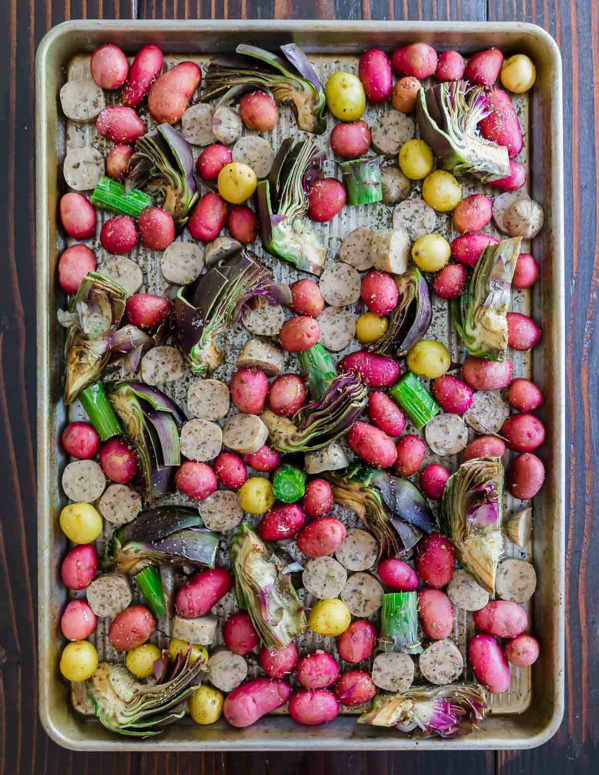 Roasted vegetables and sausage on a baking sheet.