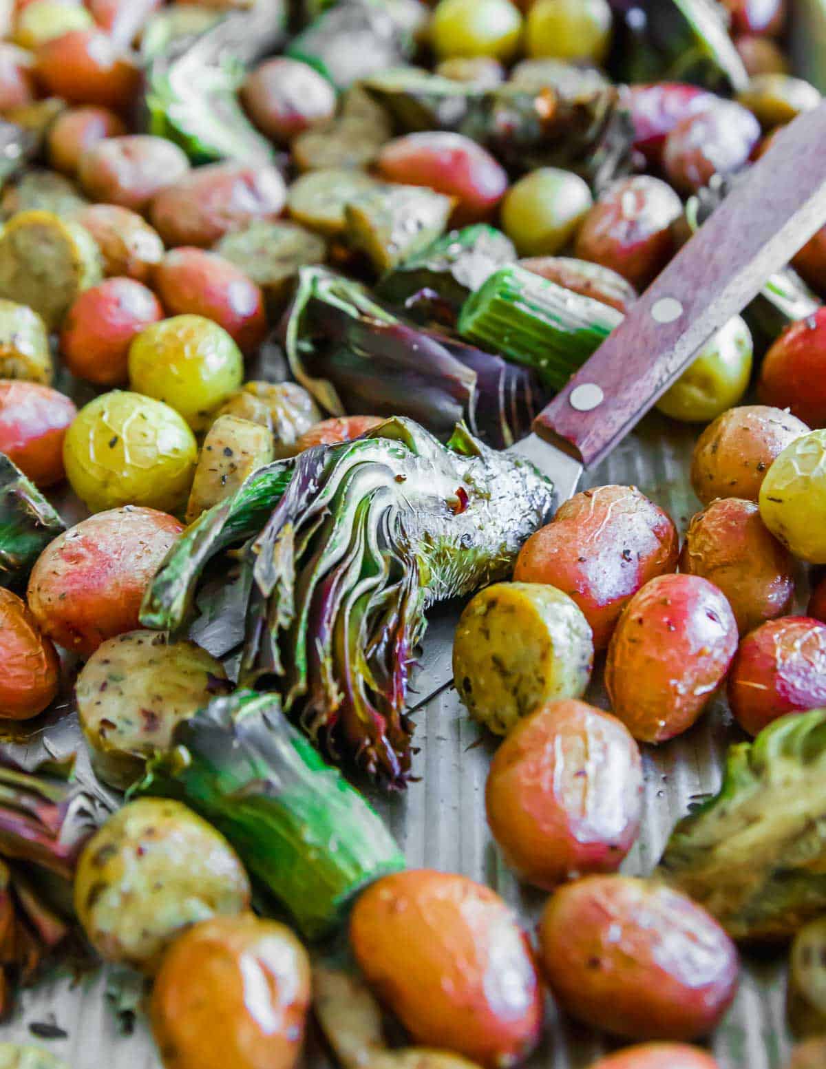 Roasted potatoes and artichokes on a baking sheet.