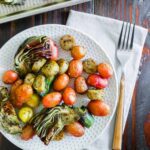Roasted vegetables and potatoes on a plate with a fork.