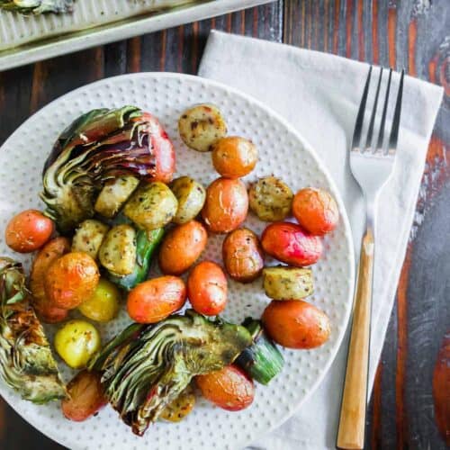 Roasted vegetables and potatoes on a plate with a fork.