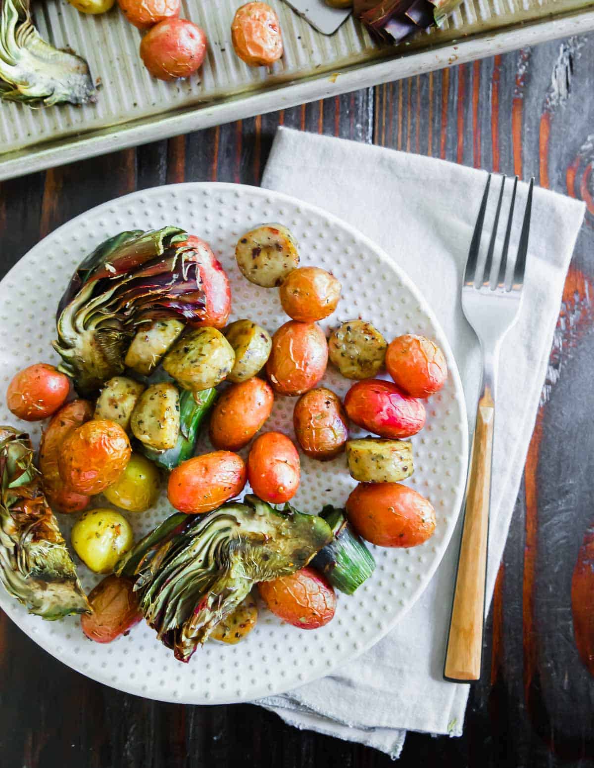 Roasted vegetables and potatoes on a plate with a fork.