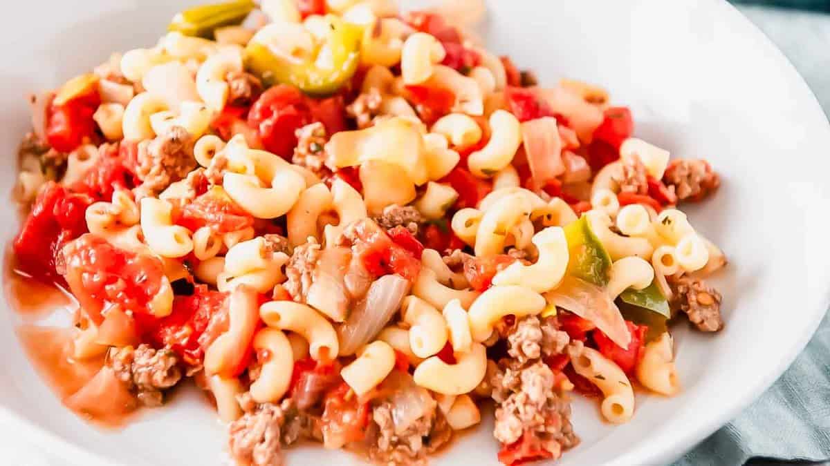 A bowl of pasta with meat, tomatoes and peppers.