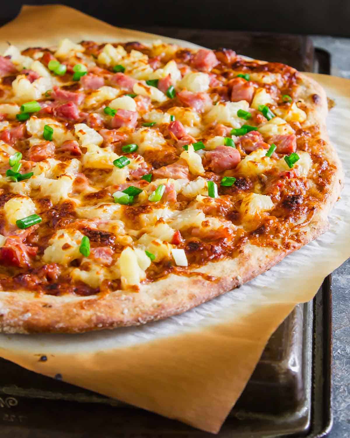 Hawaiian pizza on a baking sheet.