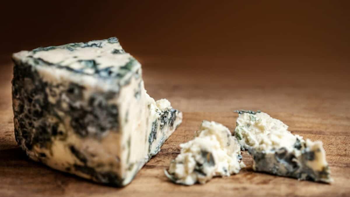 A piece of blue cheese on a wooden table.