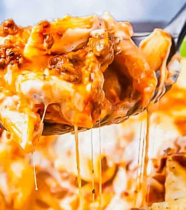 A spoonful of lasagna being taken out of the oven.