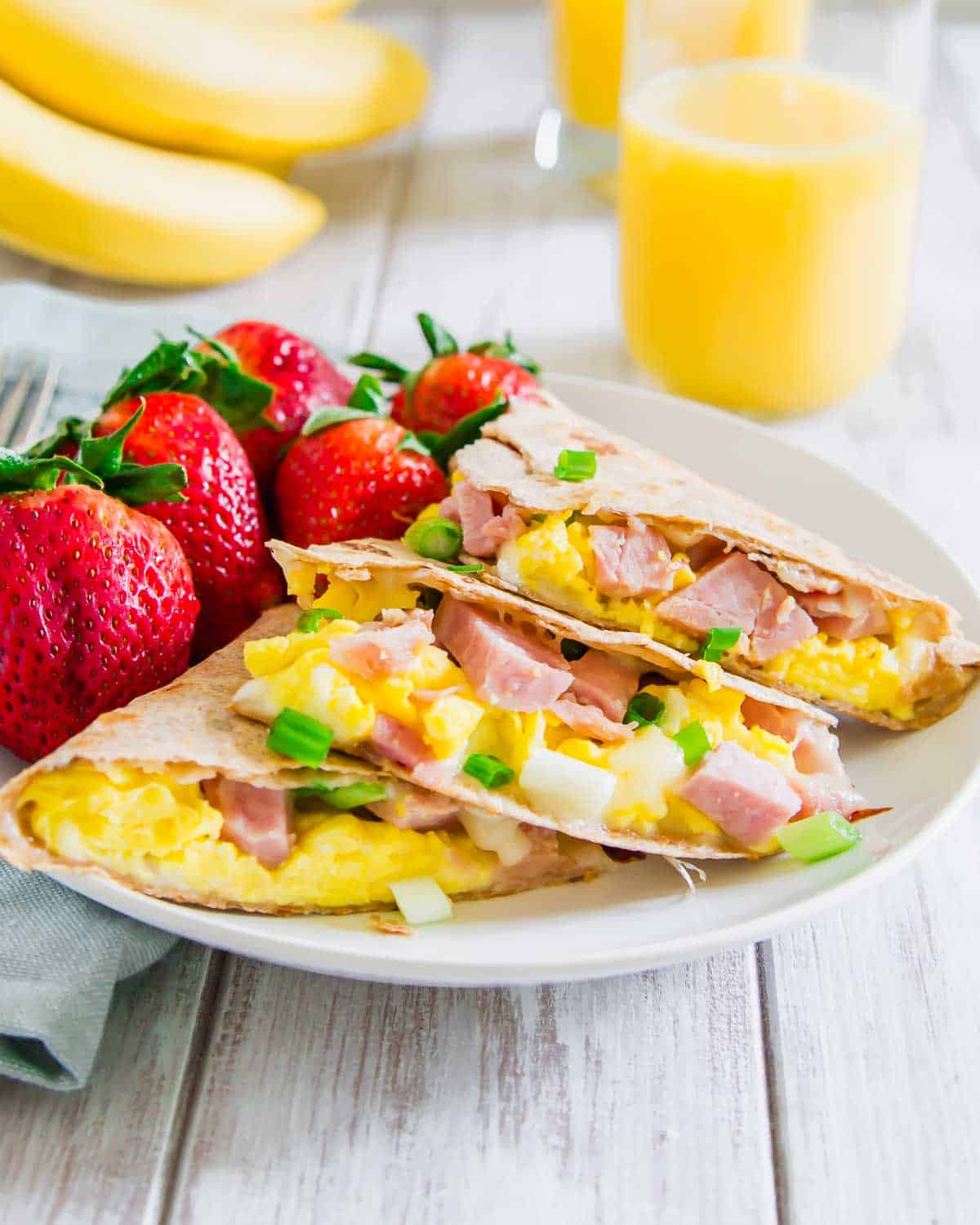 A plate with a breakfast quesadilla and a cup of orange juice.