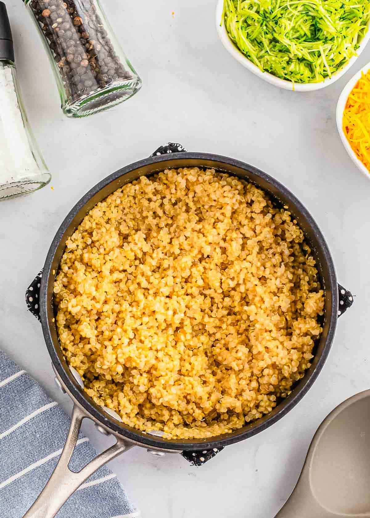 Cooked quinoa in a pot next to other ingredients.