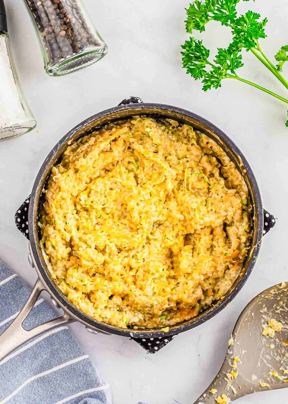 A skillet filled with cheesy quinoa and shredded zucchini.