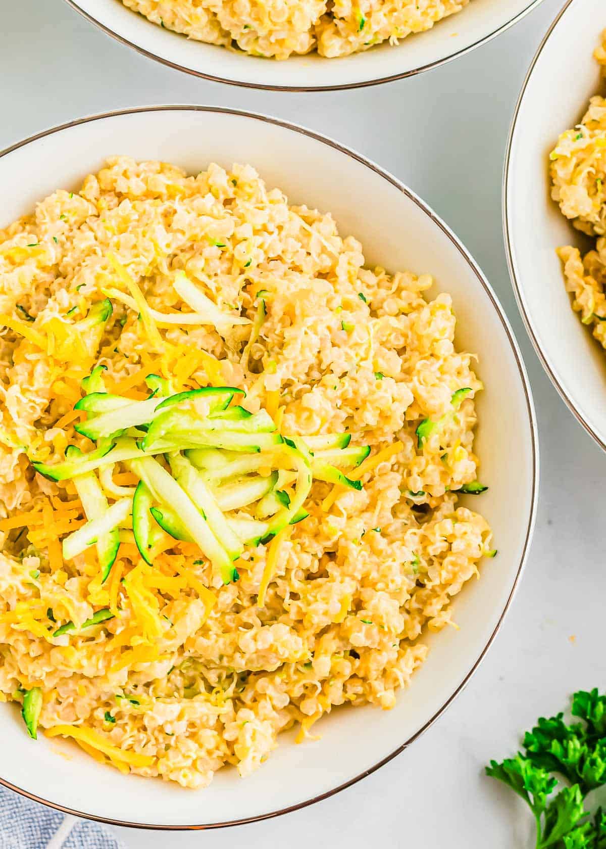 Three bowls of cheesy zucchini quinoa on a table.