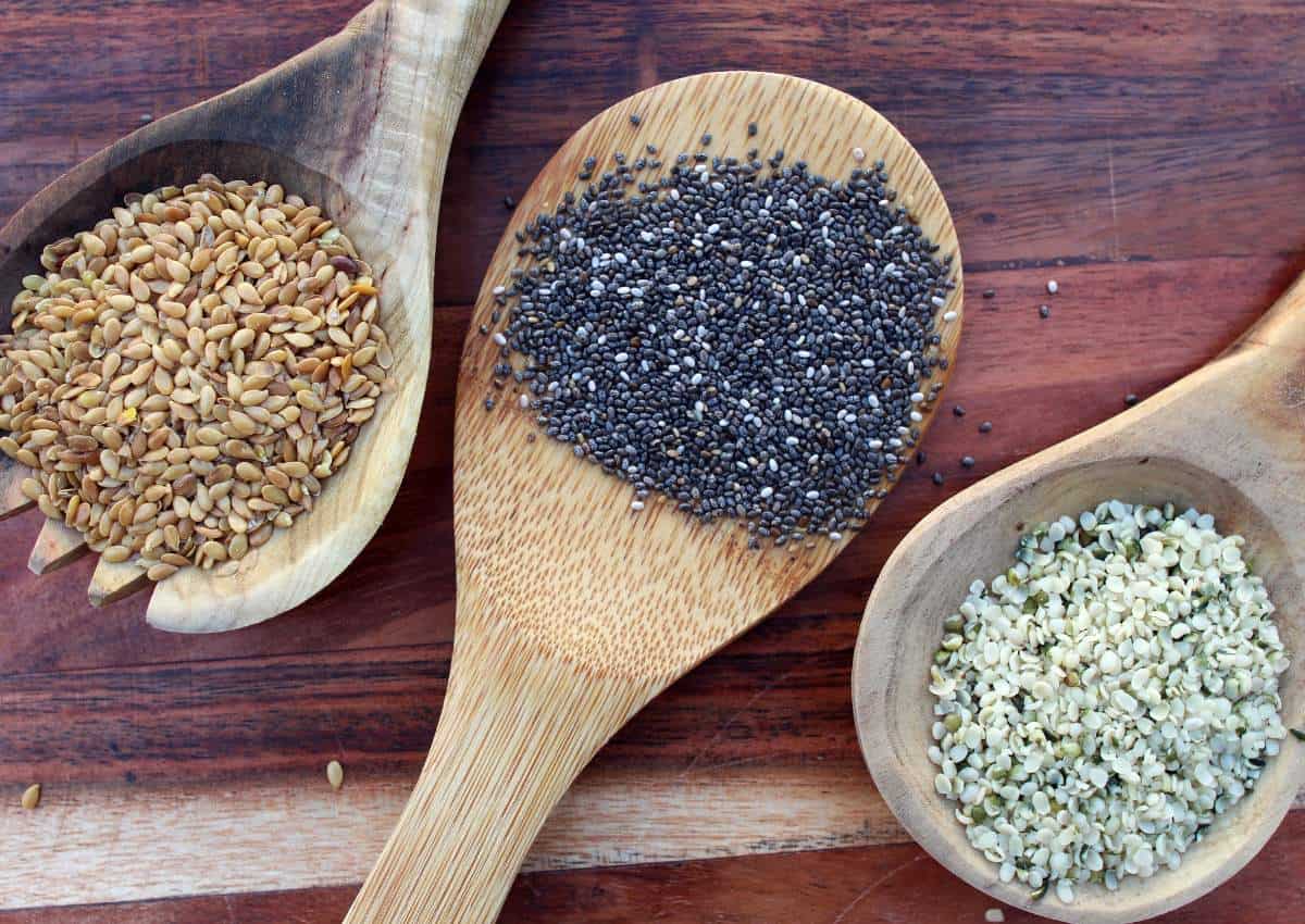 Chia seeds in wooden spoons on a wooden table.