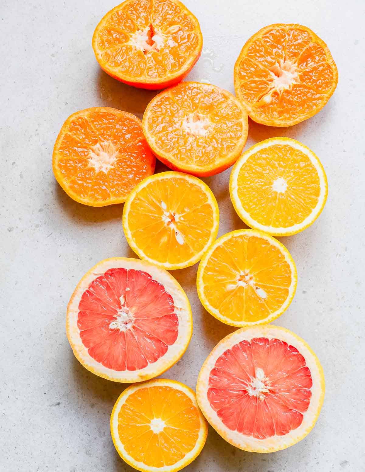 Sliced oranges and grapefruits on a white surface.
