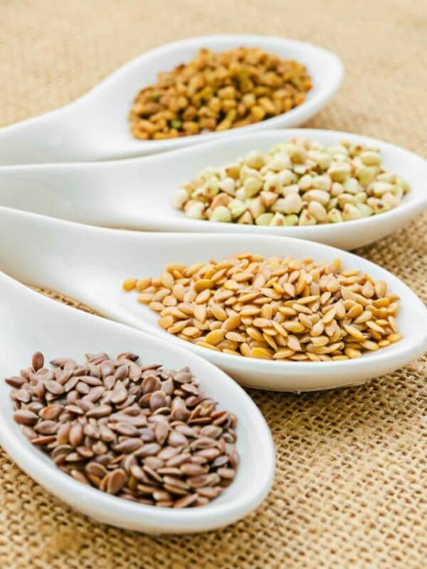 Fenugreek seeds in white spoons.