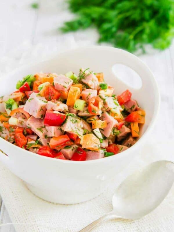 Ham and vegetable salad in a white bowl.