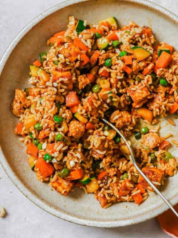 A bowl of fried rice with vegetables and carrots.