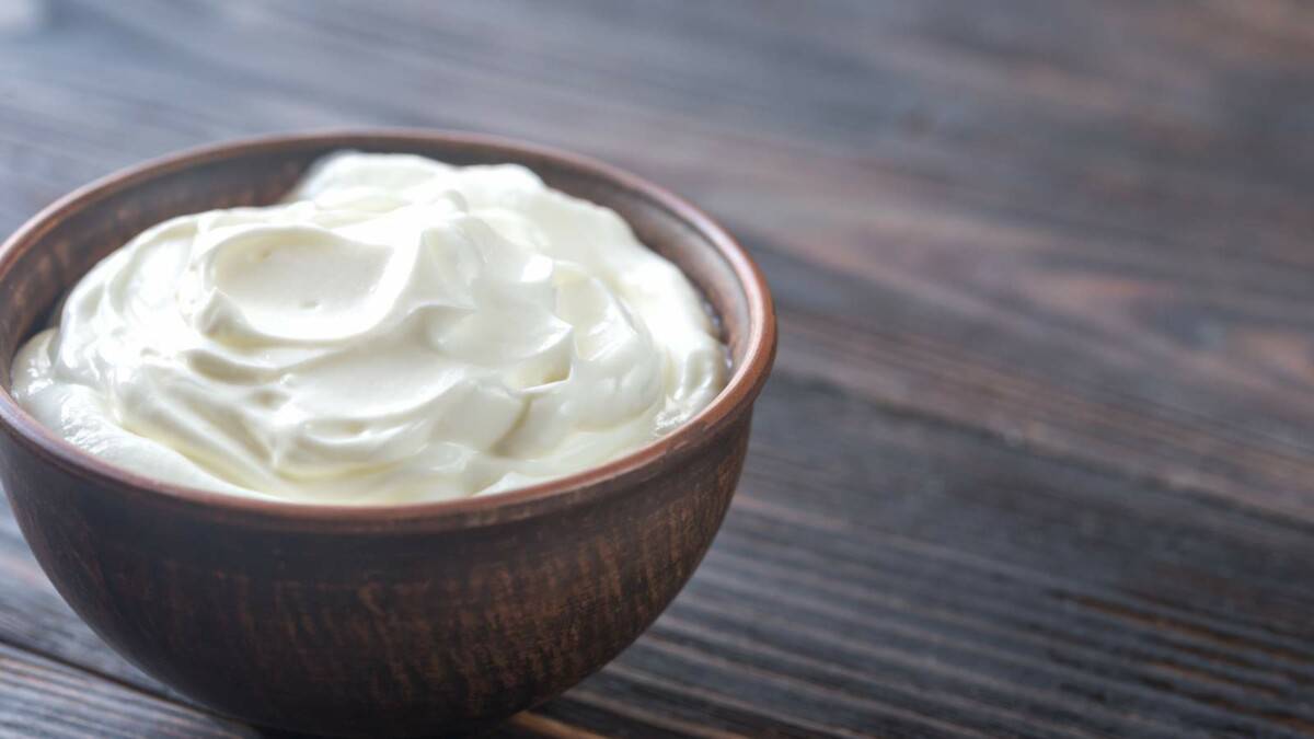 Whipped cream in a wooden bowl on a wooden table.