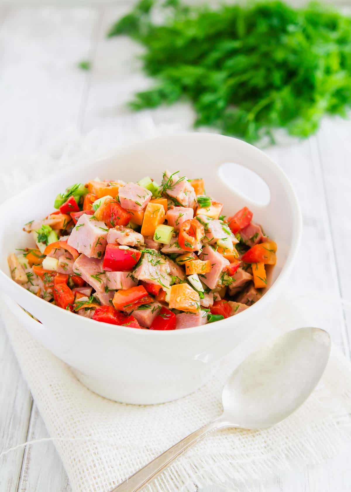 Ham salad in a white bowl on a wooden table.