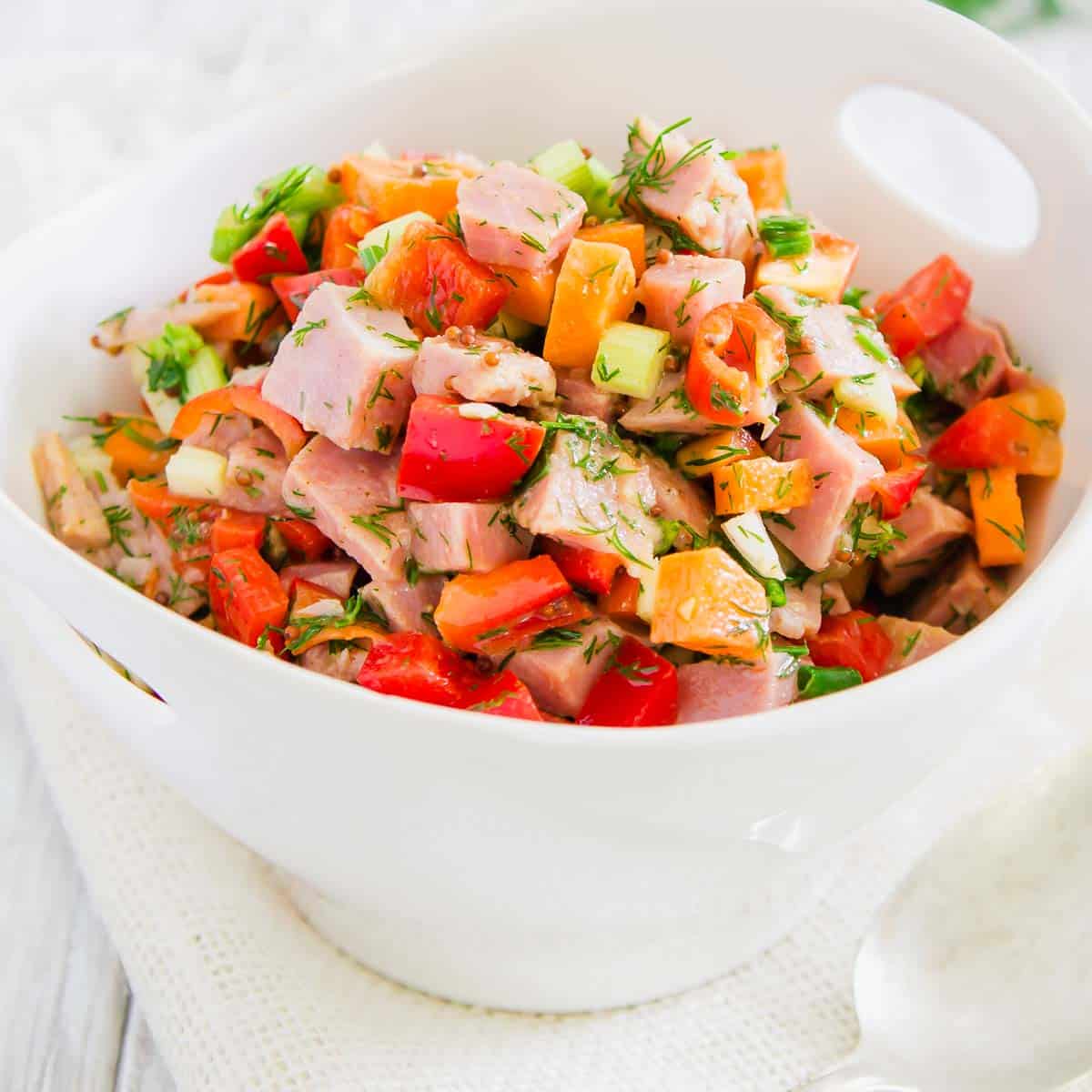 Leftover ham salad in a white bowl with a spoon.