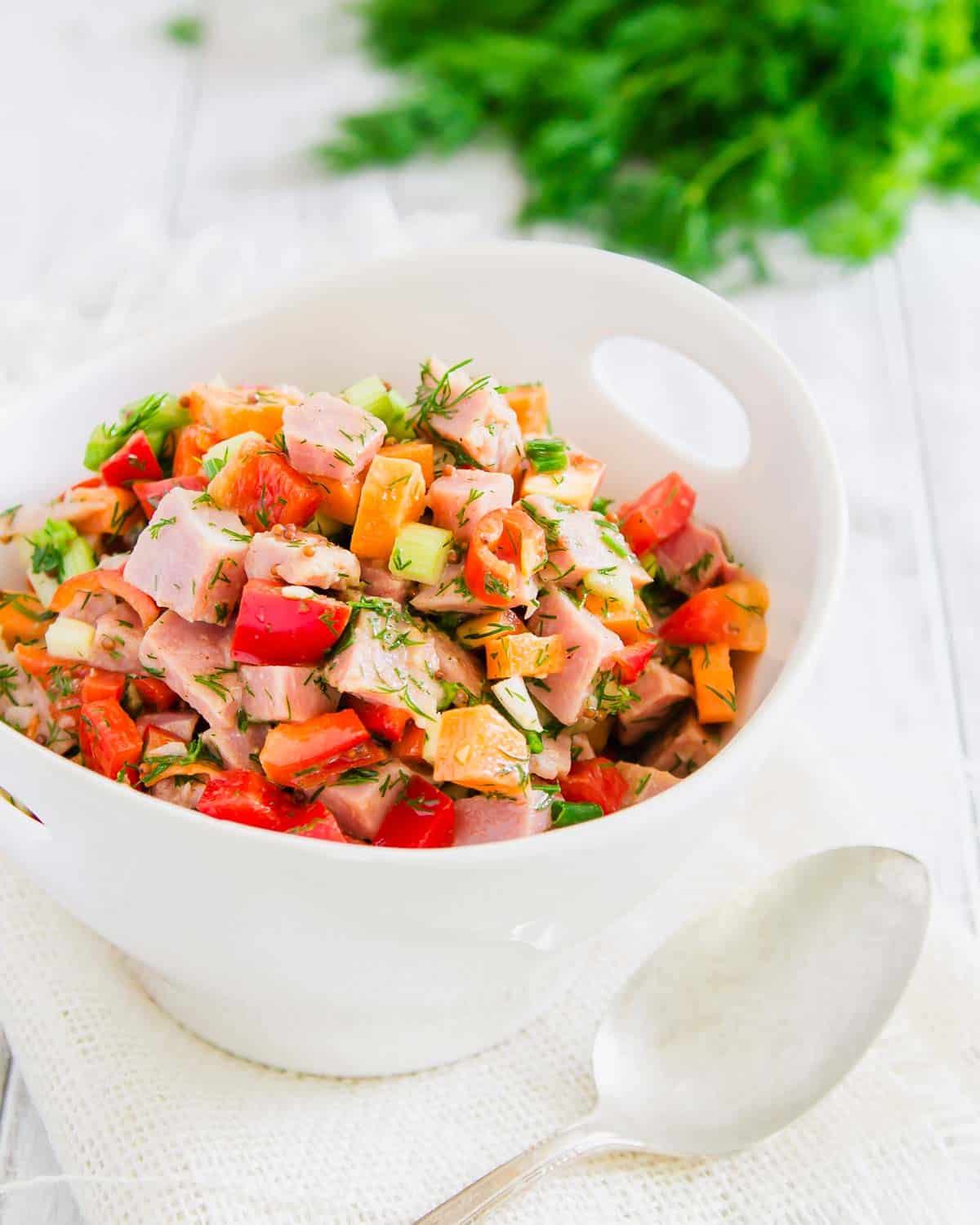 Chopped ham salad in a white bowl with a spoon.