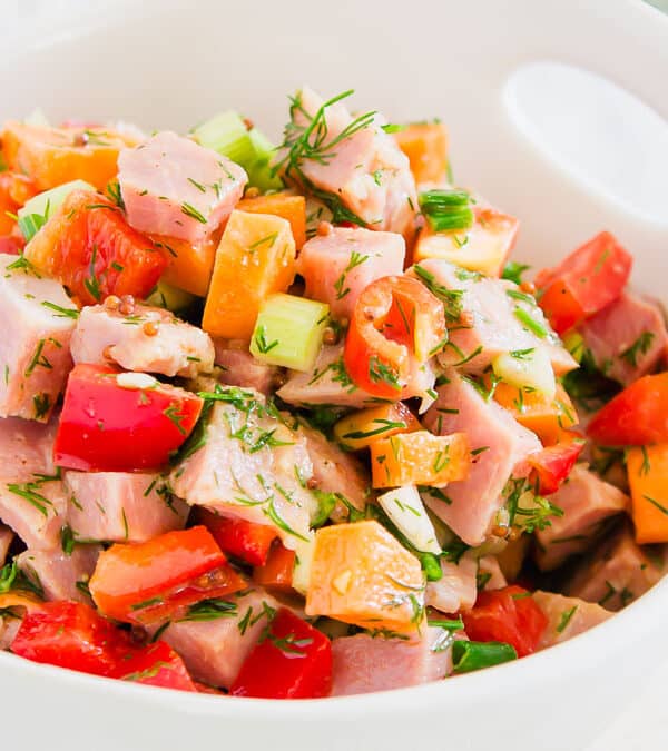 Ham salad in a white bowl with a spoon.