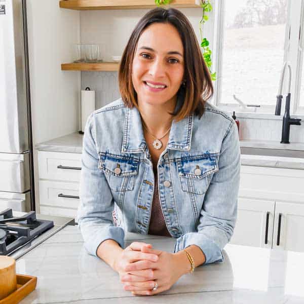 A woman in a denim jacket sitting in a kitchen, with a sidebar nearby.