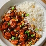 A white bowl with rice and kung pao shrimp in it.