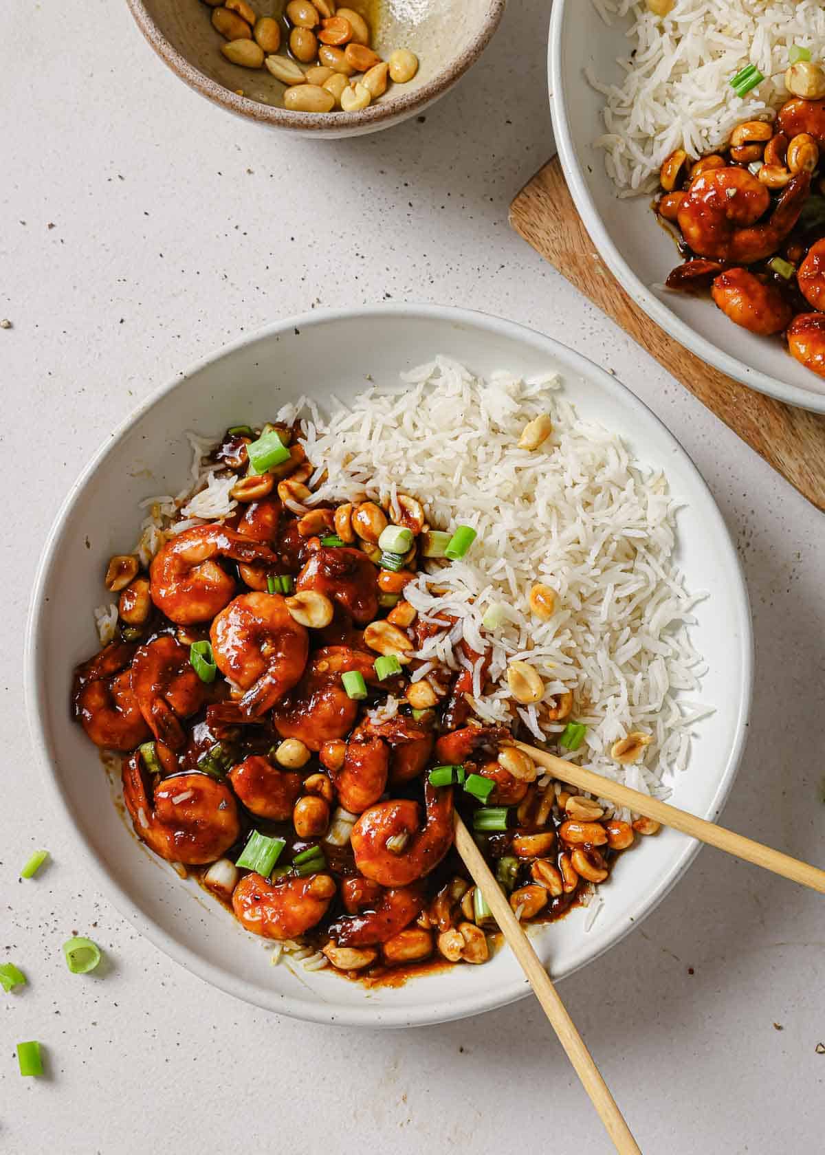 Two bowls of rice and shrimp with chopsticks.