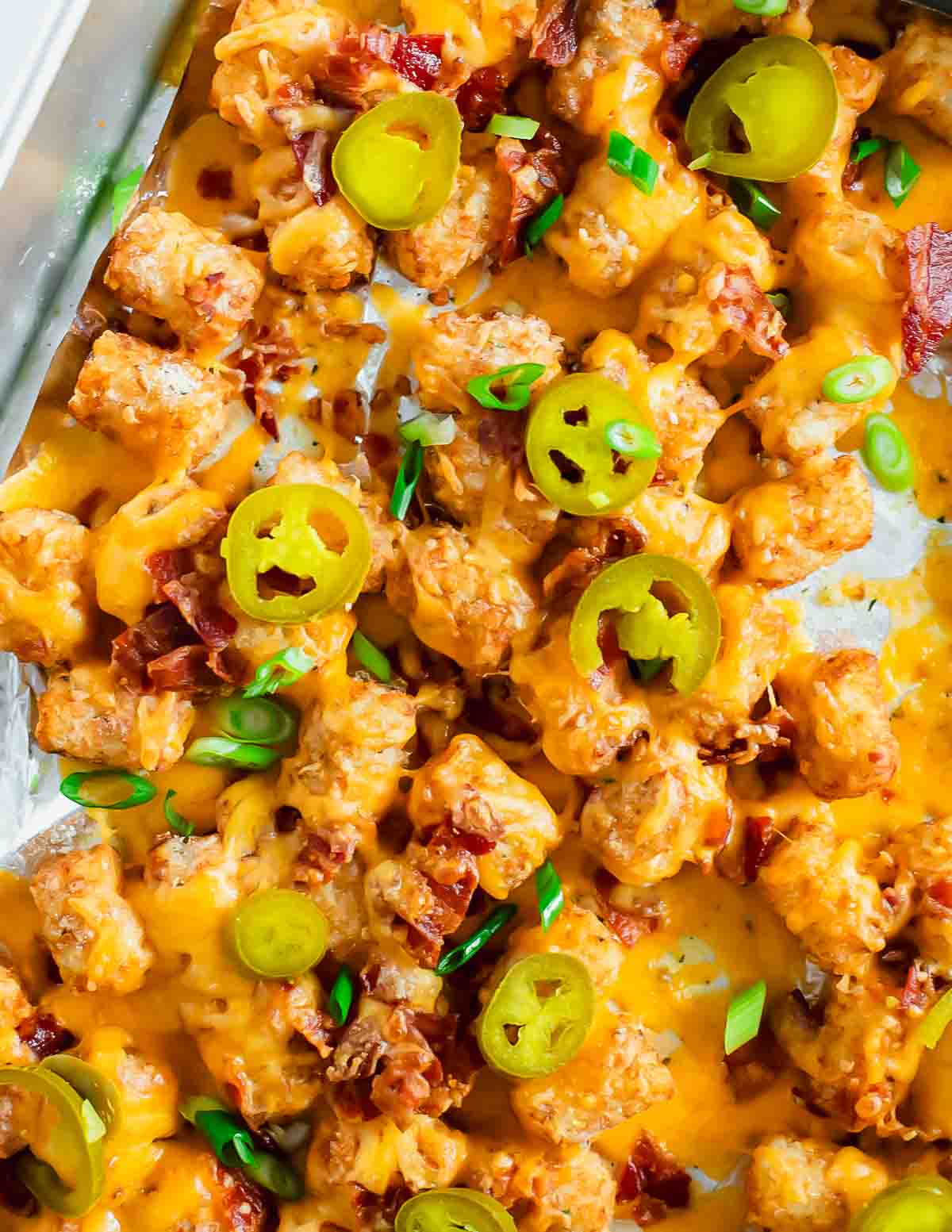 Loaded tater tots on a baking pan.