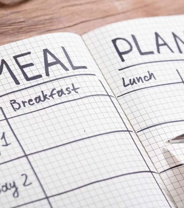 A person writing a meal plan on a notebook.