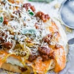A pizza on a piece of parchment paper with sweet potato and chorizo.