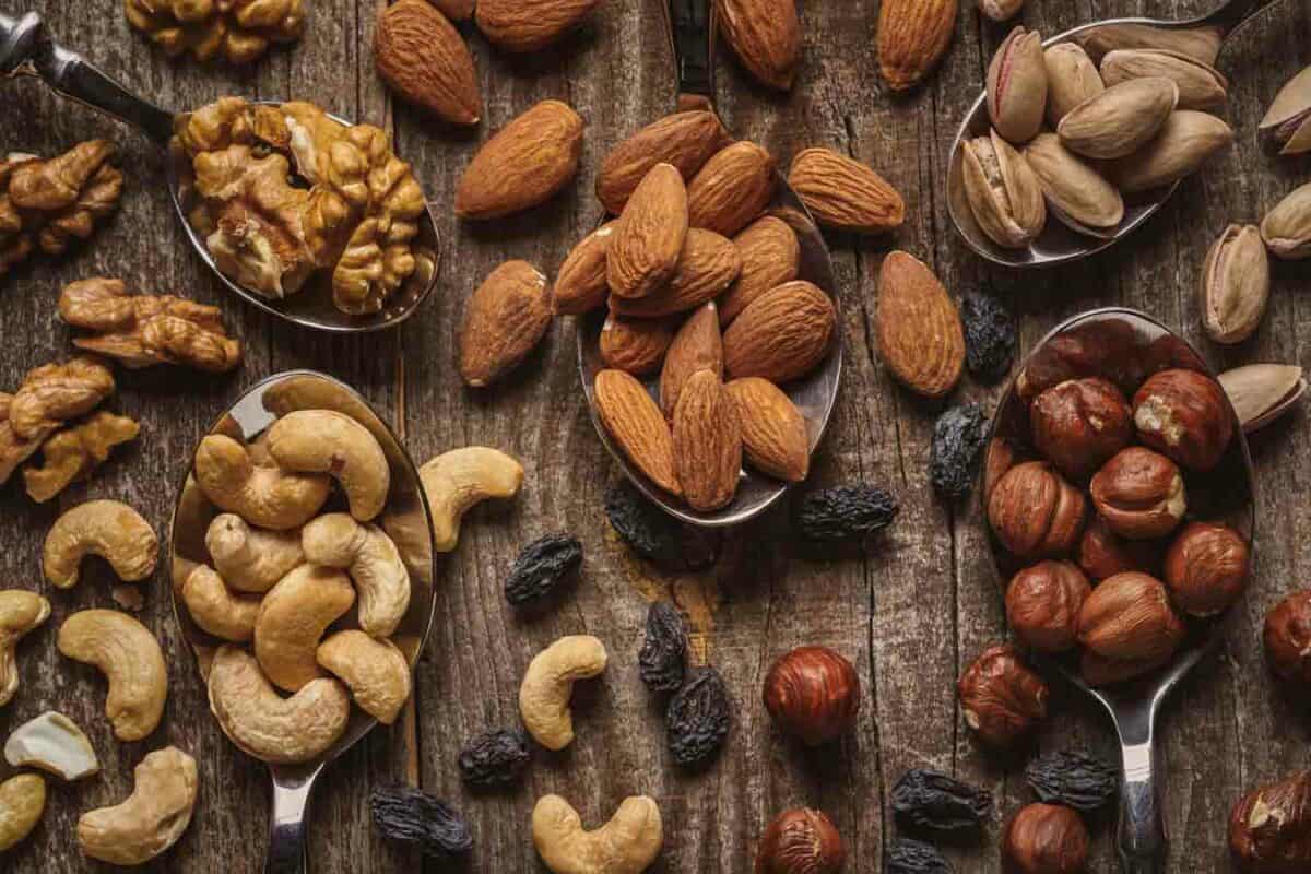 A variety of nuts in spoons on a wooden table.