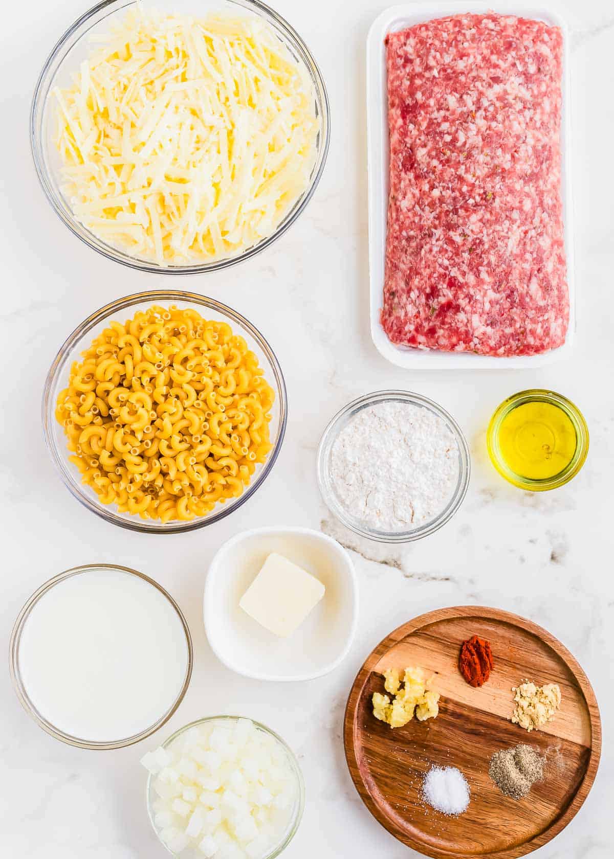 The ingredients for sausage mac and cheese are laid out on a marble table.