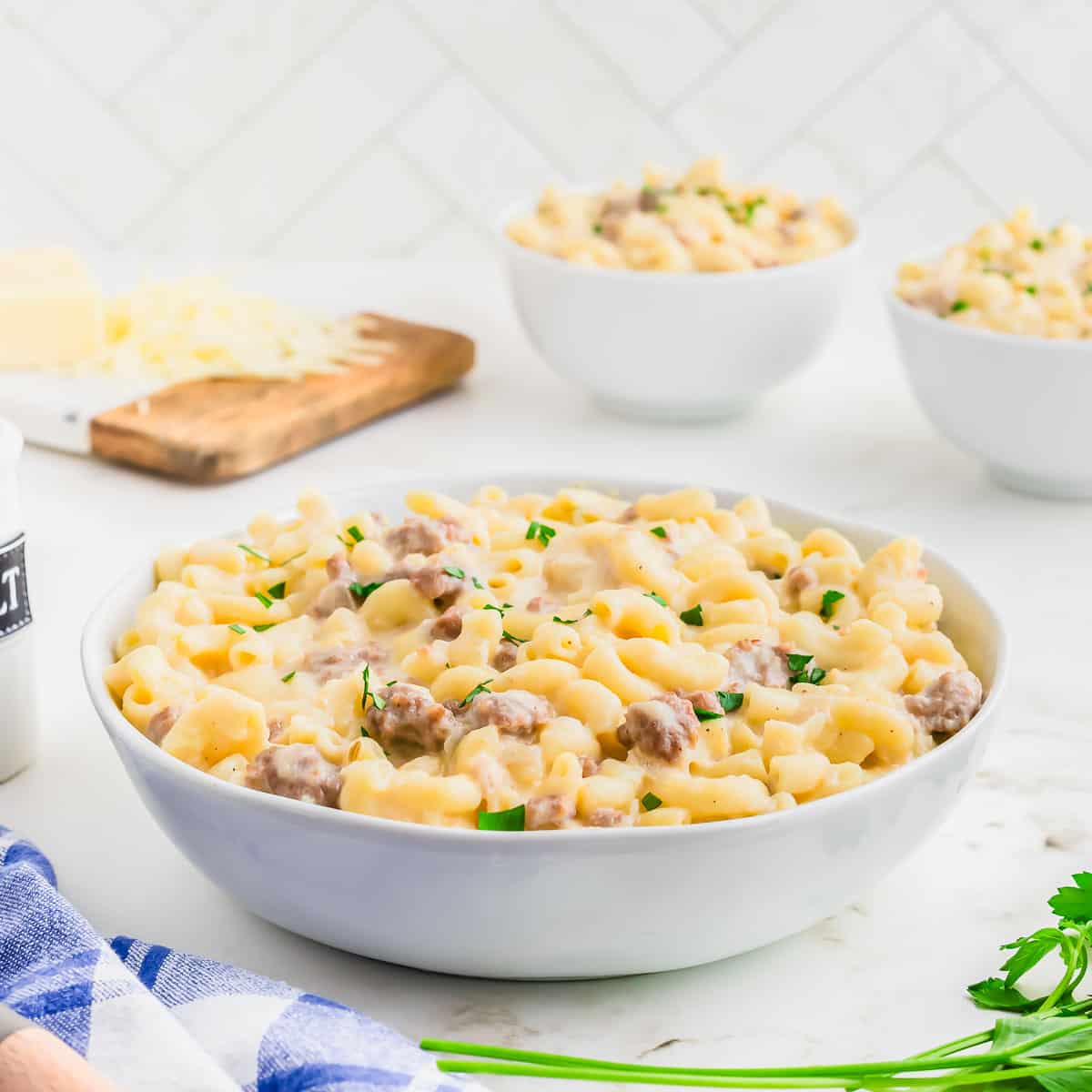 A bowl of macaroni and cheese with sausage and parsley.