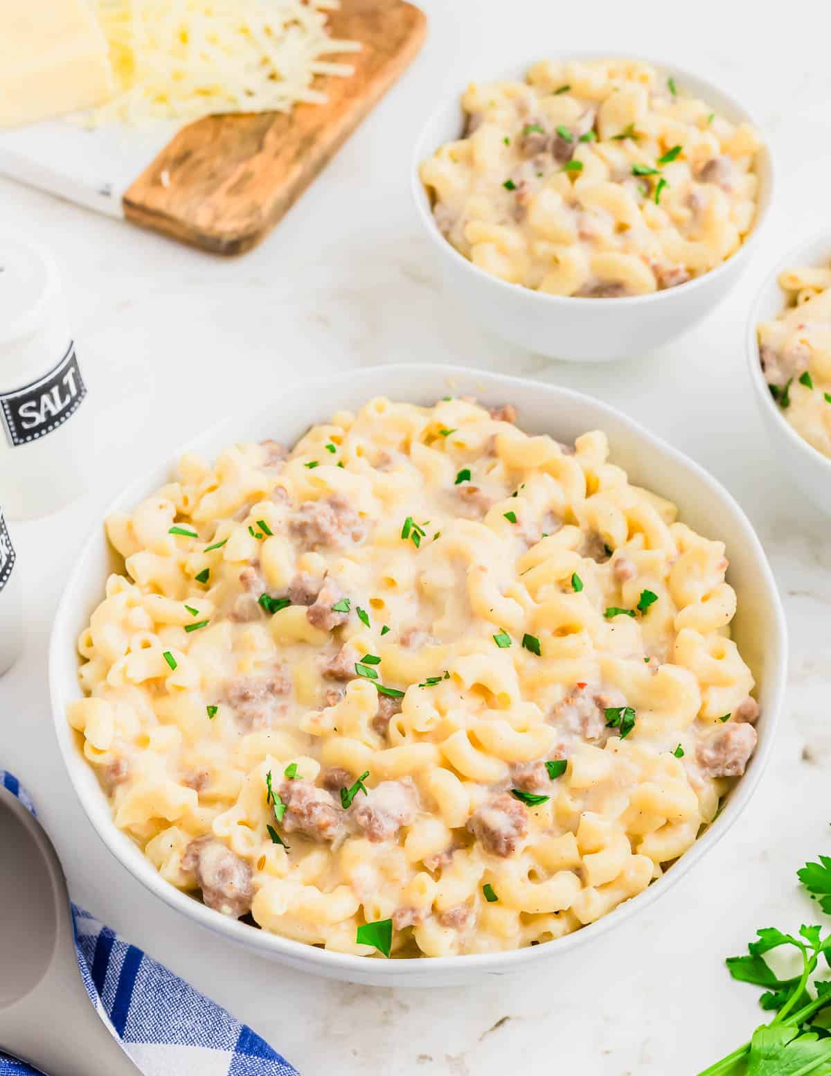 A bowl of macaroni and cheese with sausage and parmesan cheese.