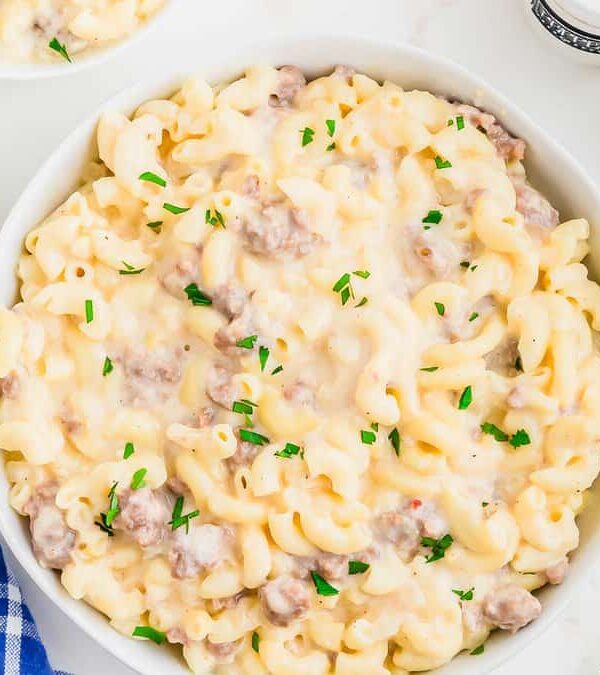 A bowl of macaroni and cheese with sausage and parsley.