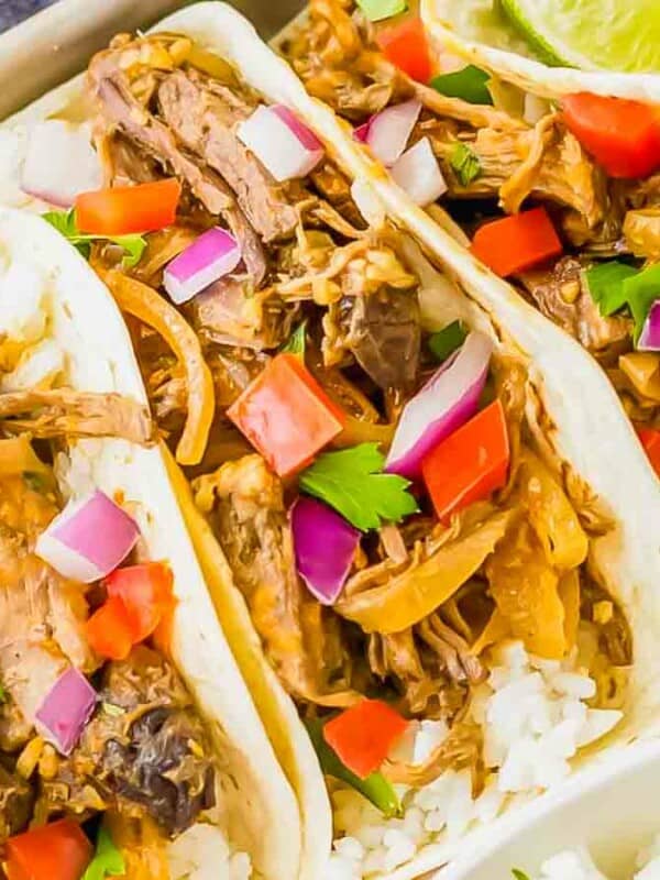 Three pulled pork tacos on a plate with rice.