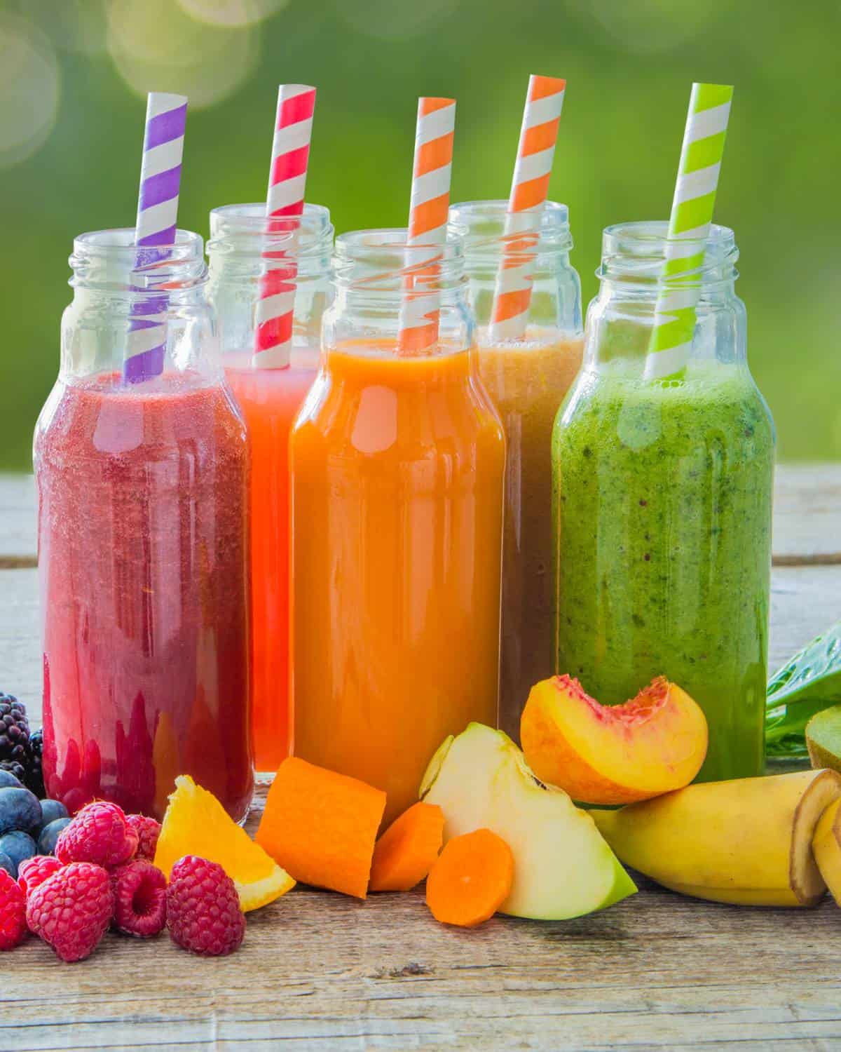 A variety of fruit and vegetable smoothies on a wooden table.