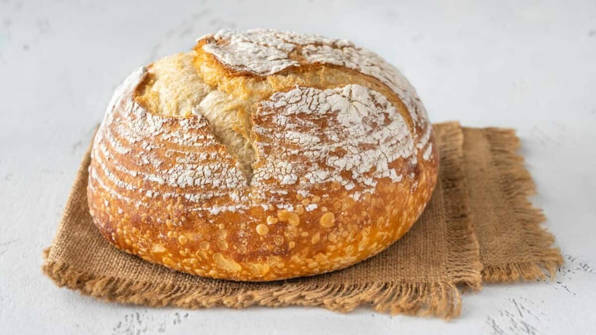 A loaf of bread sitting on a burlap cloth.