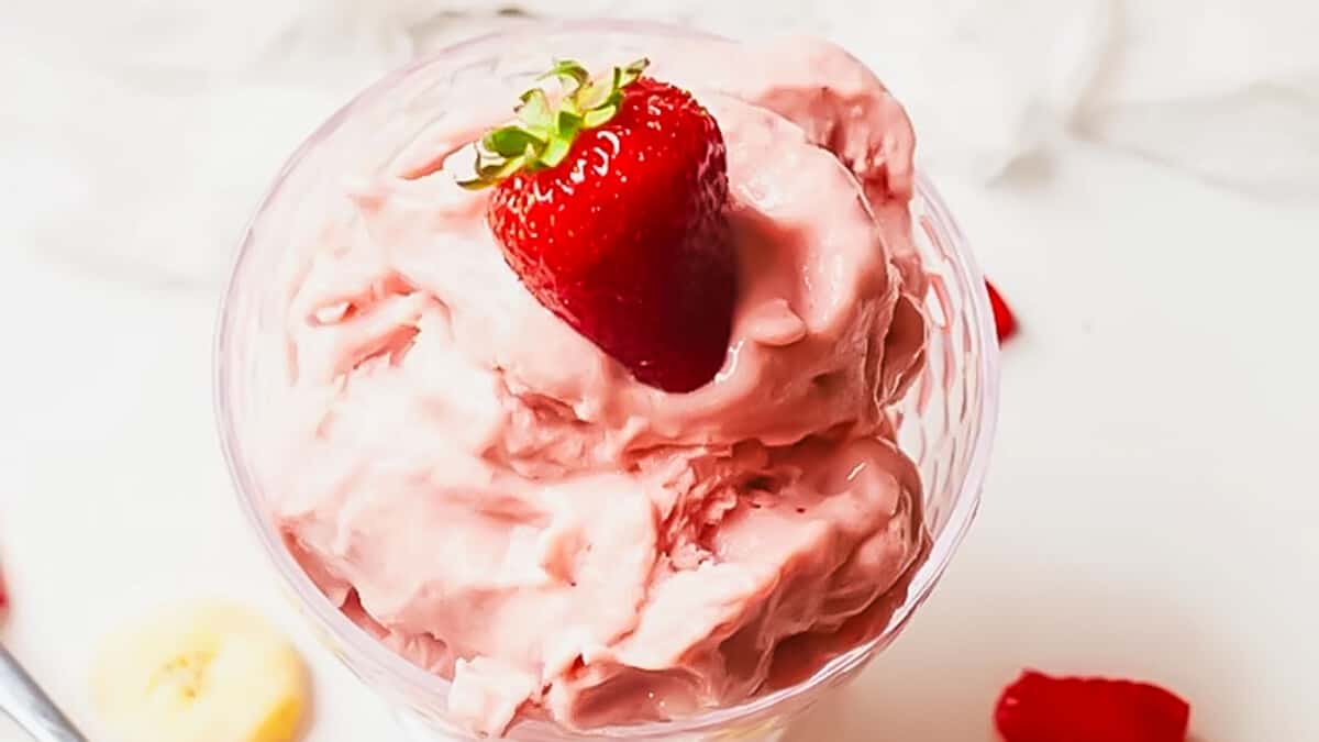 A strawberry on top of a ice cream.