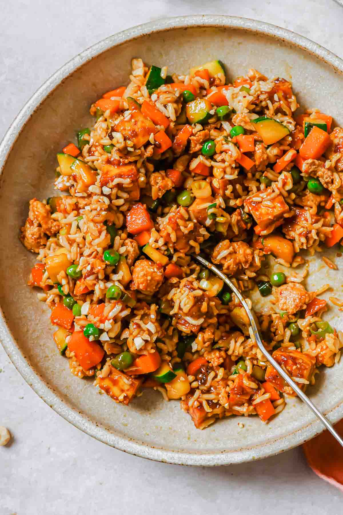 Tofu fried rice on a dish with a fork.