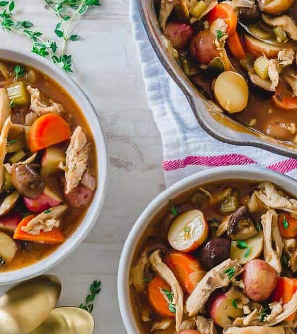 Two bowls of chicken soup with vegetables and potatoes.