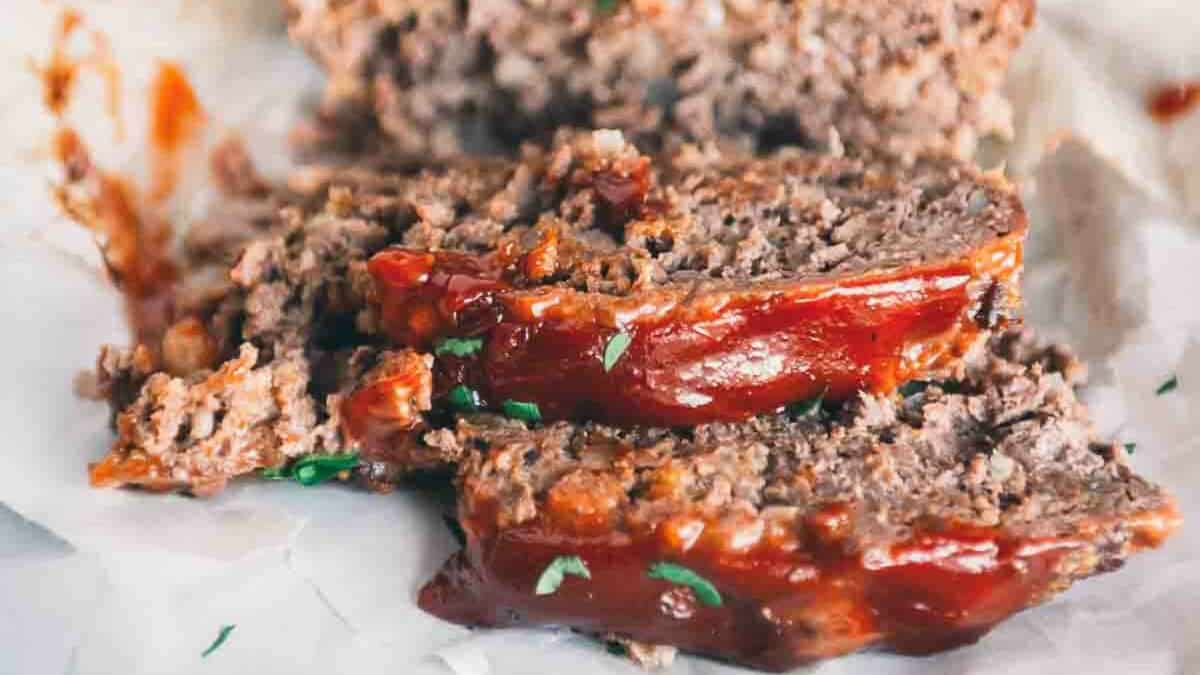 A slice of meatloaf with bbq sauce on top.