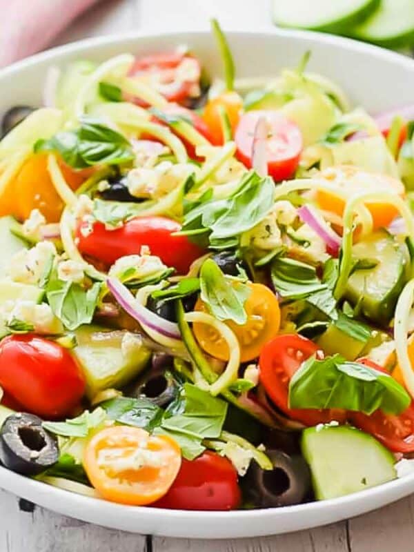 A bowl of salad with tomatoes, cucumbers and olives.