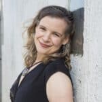 Michelle, a woman in a black dress, leaning against a wall.