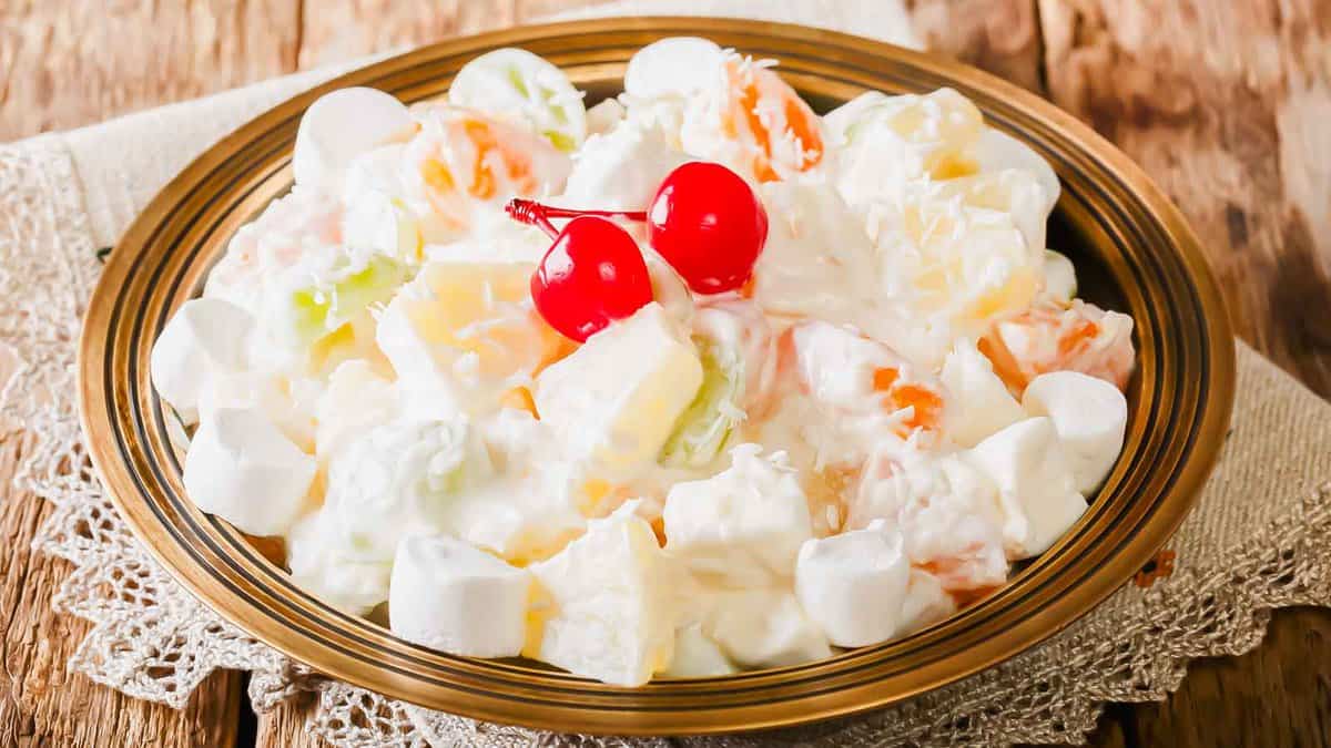 A bowl of fruit salad with a cherry on top.