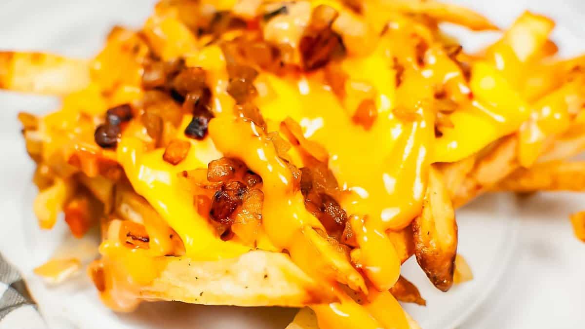 A plate of french fries covered in cheese and bacon.