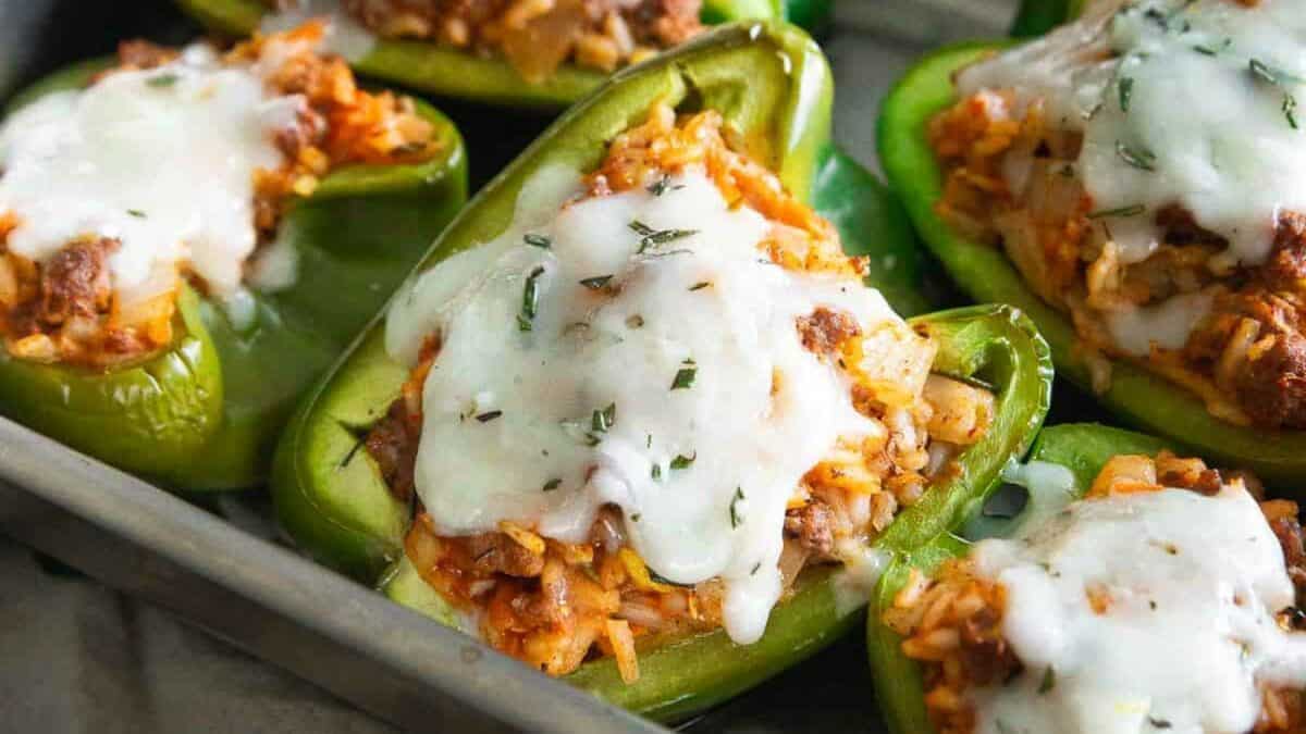 Stuffed peppers with meat and cheese in a baking pan.