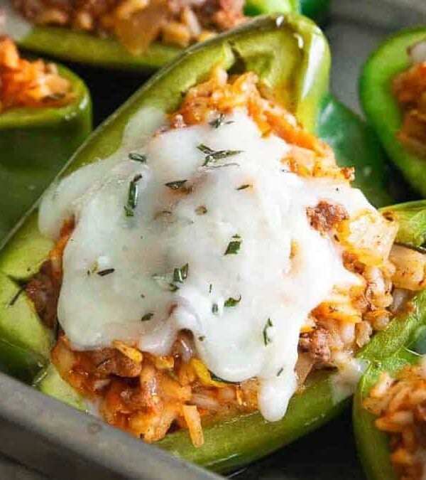 Stuffed peppers with meat and cheese in a baking pan.