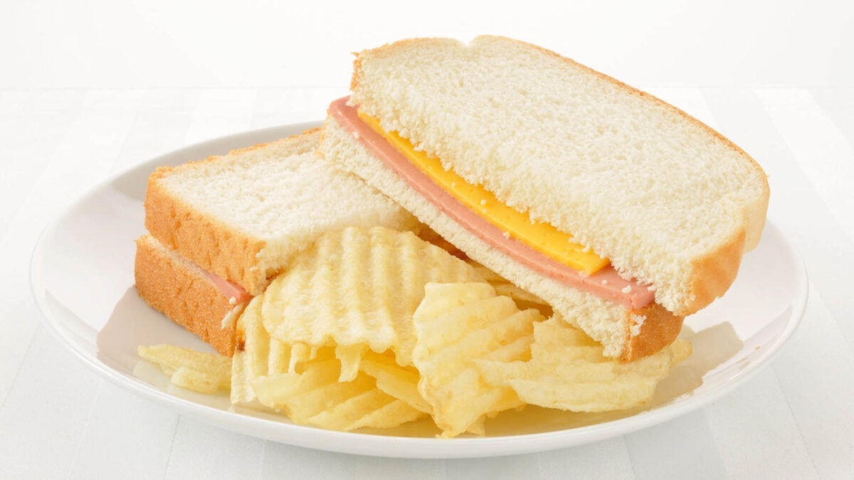A white plate with a sandwich and chips.