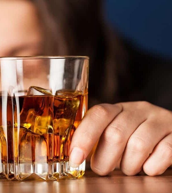 A woman is holding a glass of whiskey.